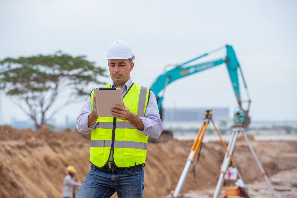 Construction engineer wear safety uniform under inspection and survey workplace by tablet with excav